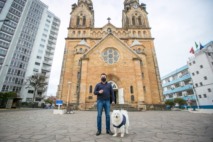 Marcius Machado com a cachorra Alanis em frente à catedral de Lages